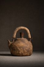 Rustic brown teapot with a textured handle on a dark background