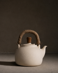 White ceramic teapot with a brown handle on a dark background